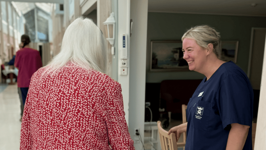 Omsorgspersonal ler mot äldre person