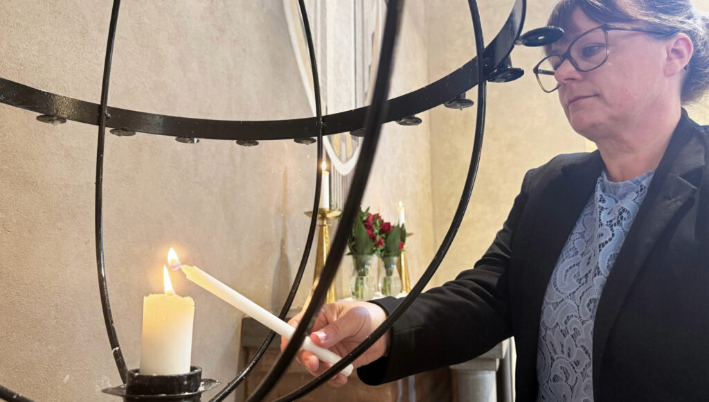 Kvinna tänder ljus i kyrka