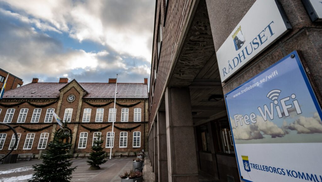 En tegelbyggnad med texten Rådhuset på en skylt i förgrunden bredvid en skylt om gratis wifi.