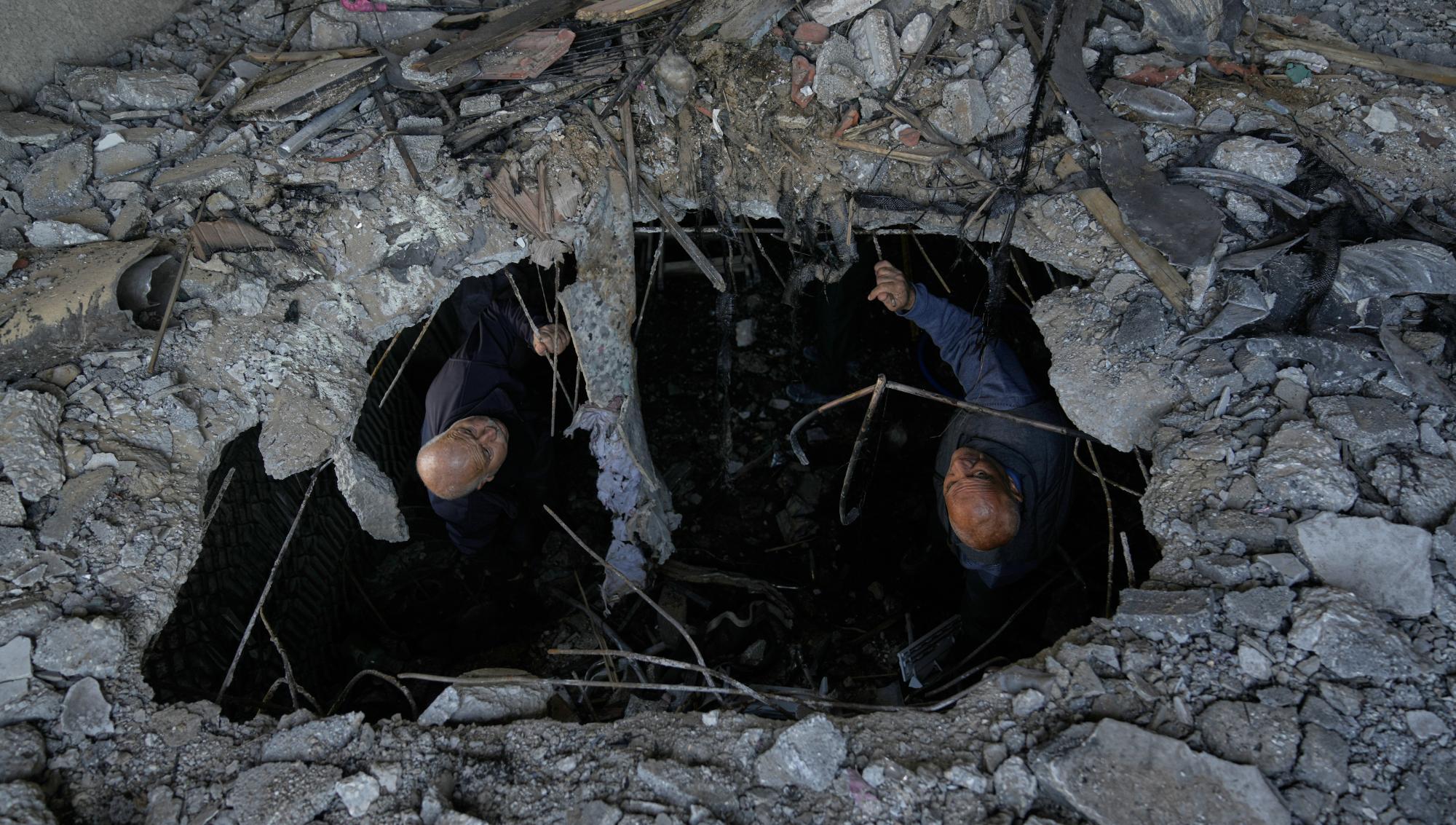 Två män blickar upp från ett stort hål i ett raserat betonggolv i ett hus på Västbanken efter att en iransk raket slagit ner i samband med de pågående striderna i Mellanöstern. Foto: Majdi Mohammed/TT