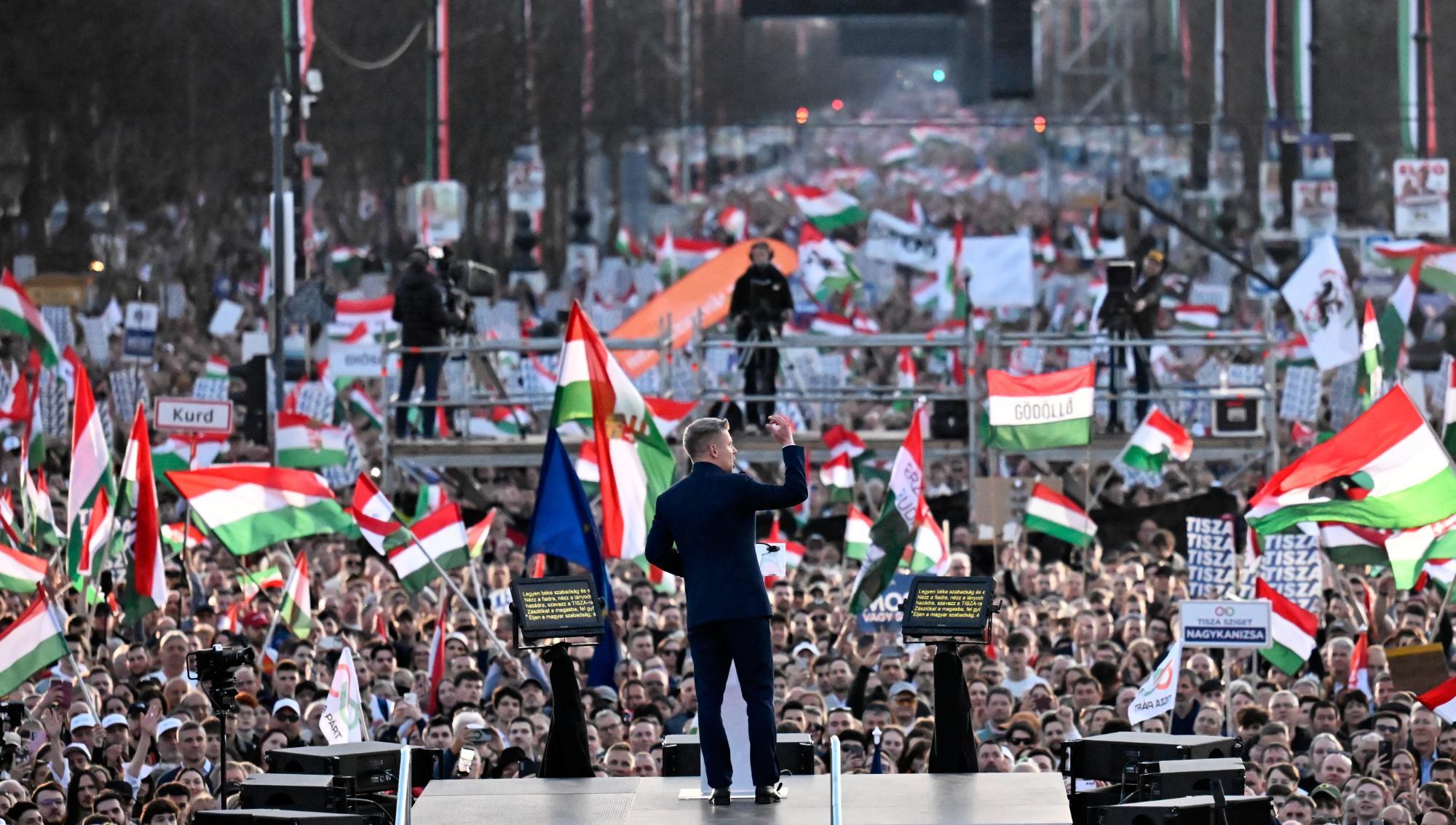 Peter Magyar talar till en stor folksamling med vajande ungerska flaggor under ett politiskt kampanjmöte. Tusentals människor har samlats på gatorna för att lyssna på oppositionspolitikern under marschen i Ungern. Foto: Denes Erdos/TT