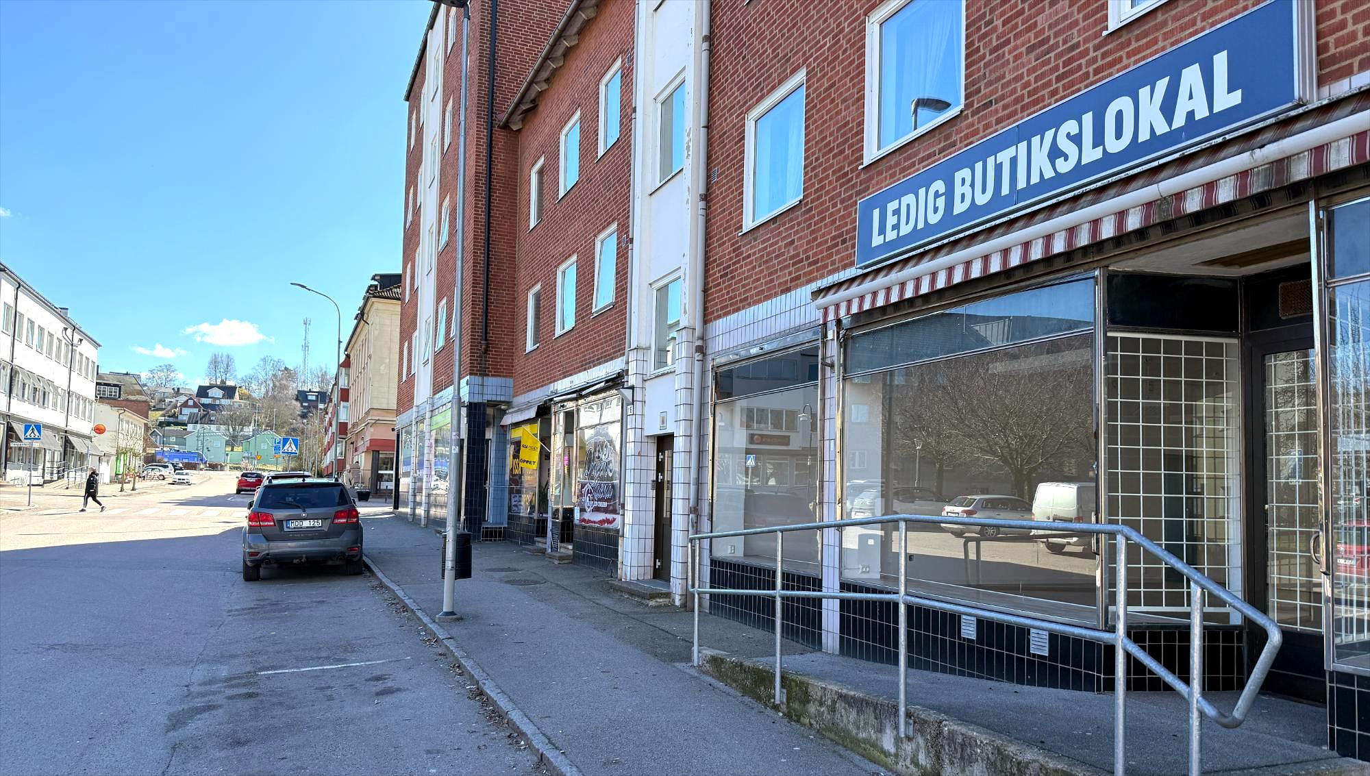 En skylt om ledig butikslokal hänger över de tomma skyltfönstren längs en gata i Åstorp.