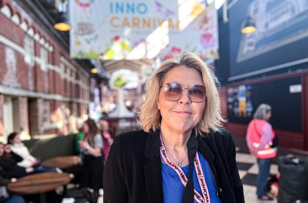 Porträtt av kvinna i solglasögon och mörk kavaj framför en banderoll för InnoCarnival.