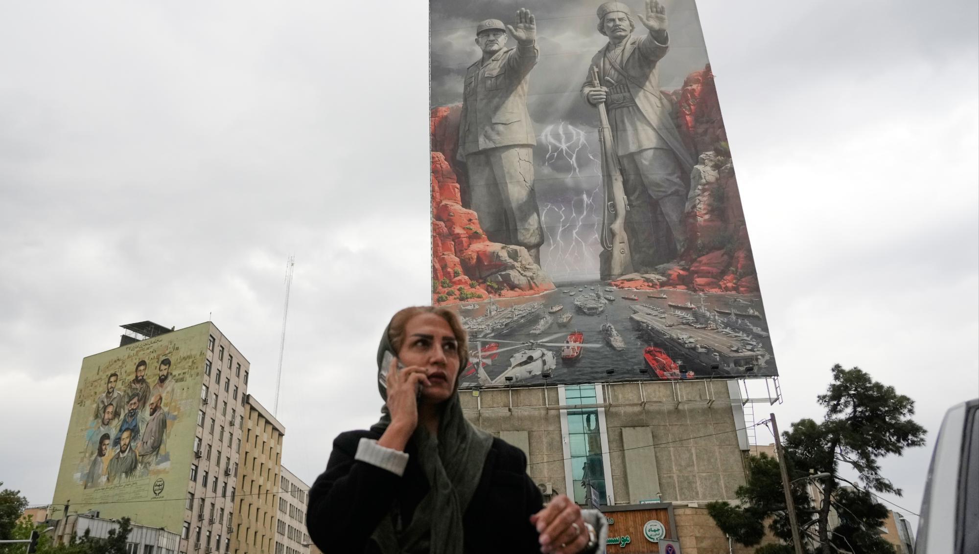 En kvinna i Teheran passerar en storskalig propagandatavla som hyllar Irans militära styrka och historiska försvar. Foto: Vahid Salemi/TT