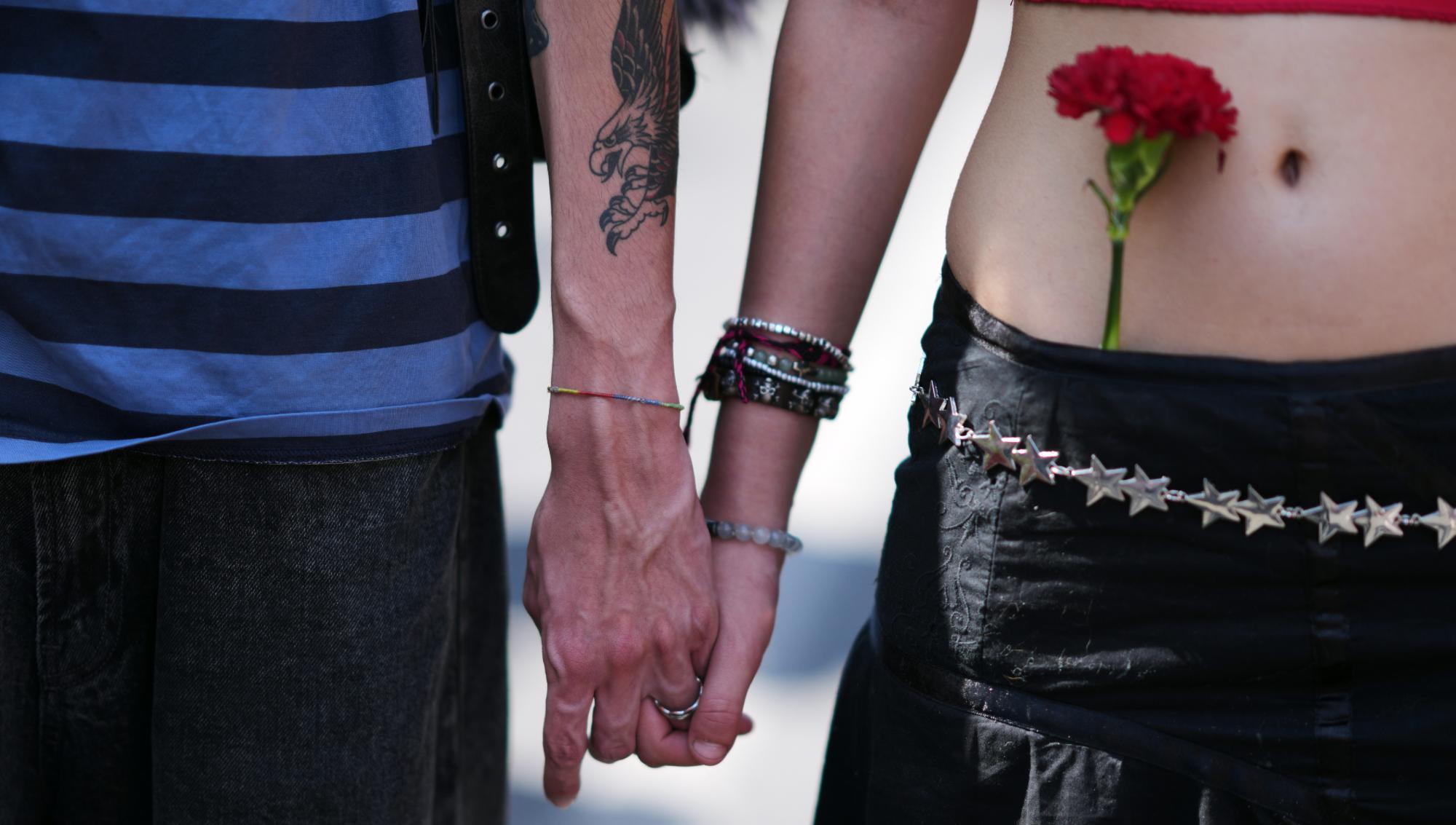 Ett ungt par håller varandra i händerna medan de tågar tillsammans med tiotusentals andra längs avenyn Liberdade i Lissabon, lördagen den 25 april 2026, för att fira årsdagen av Nejlikerevolutionen den 25 april 1974 som återinförde demokratin i Portugal. Foto: Armando Franca/TT