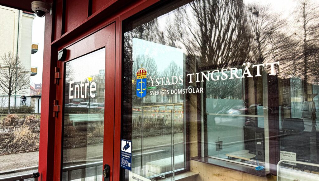 Ingången till Ystads tingsrätt med texten Sveriges domstolar på en glasruta.