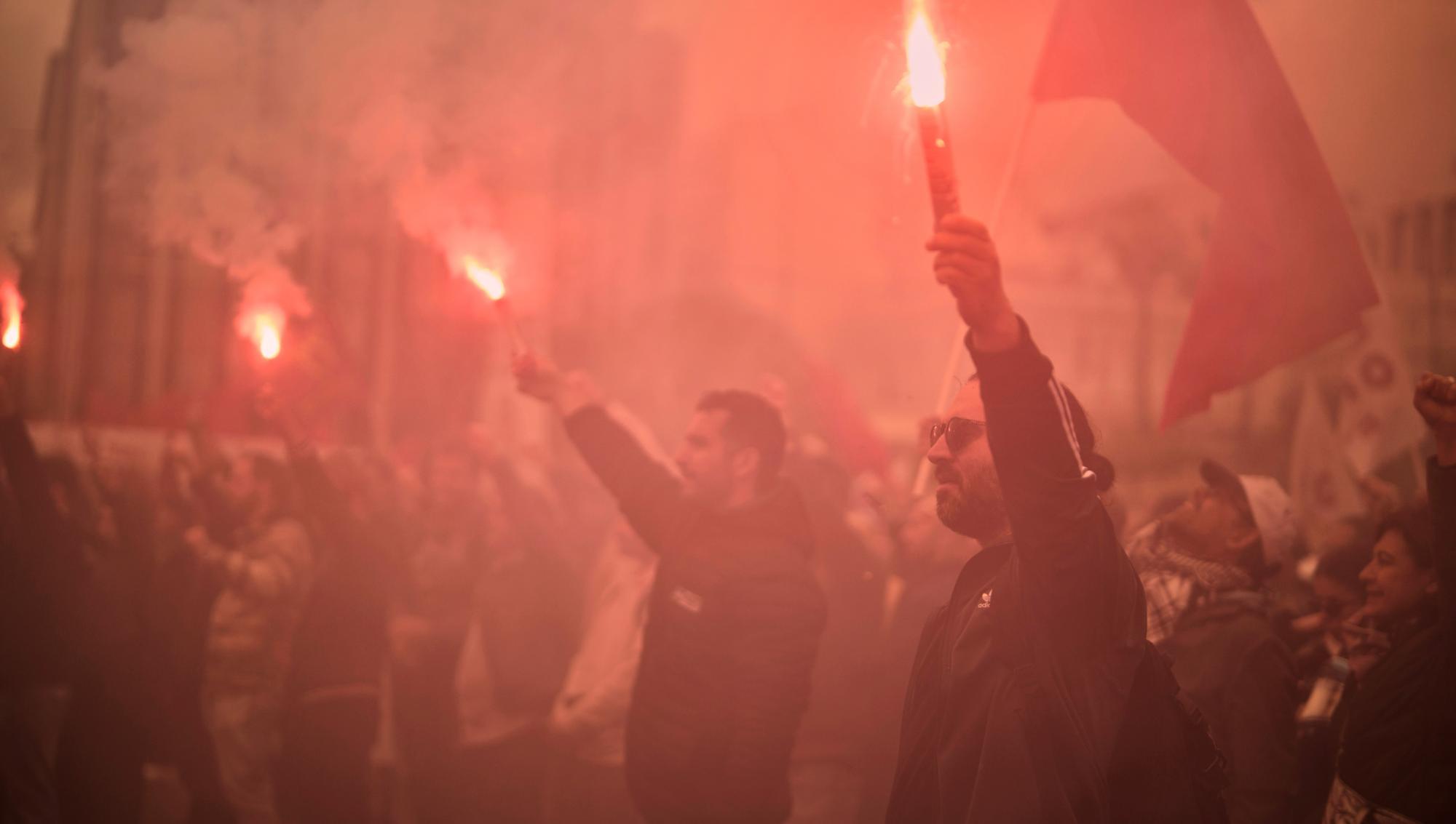 Demonstranter manifesterar med bengaliska eldar och flaggor under första maj-firandet i Grekland. Foto: Petros Giannakouris/TT