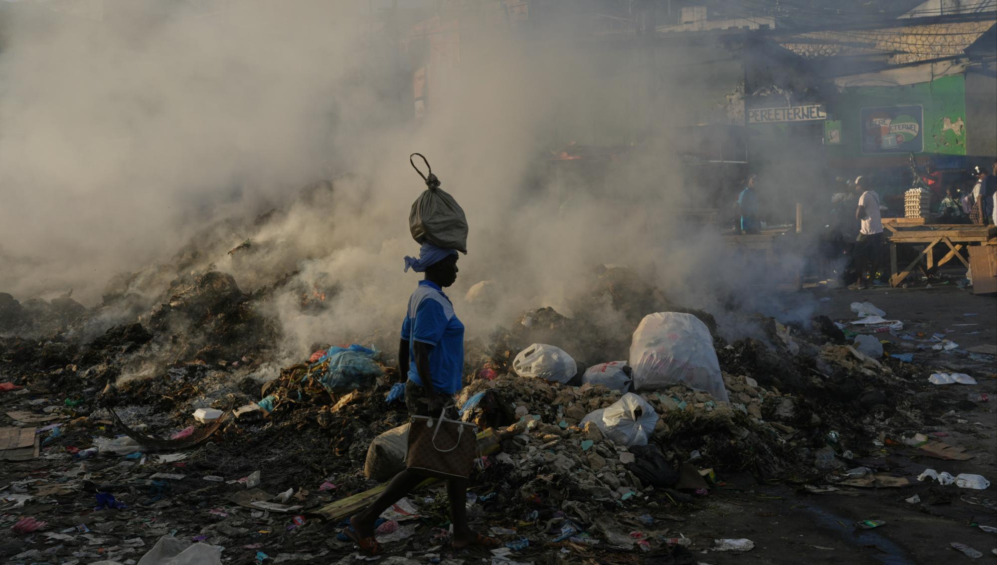 En kvinna passerar brinnande sopberg i Haitis huvudstad Port-au-Prince i maj 2026. Foto: Odelyn Joseph/TT