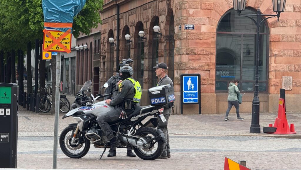 Poliser i insatsutrustning och en mc-polis vid Stortorget i Helsingborg bredvid en röd stenbyggnad.