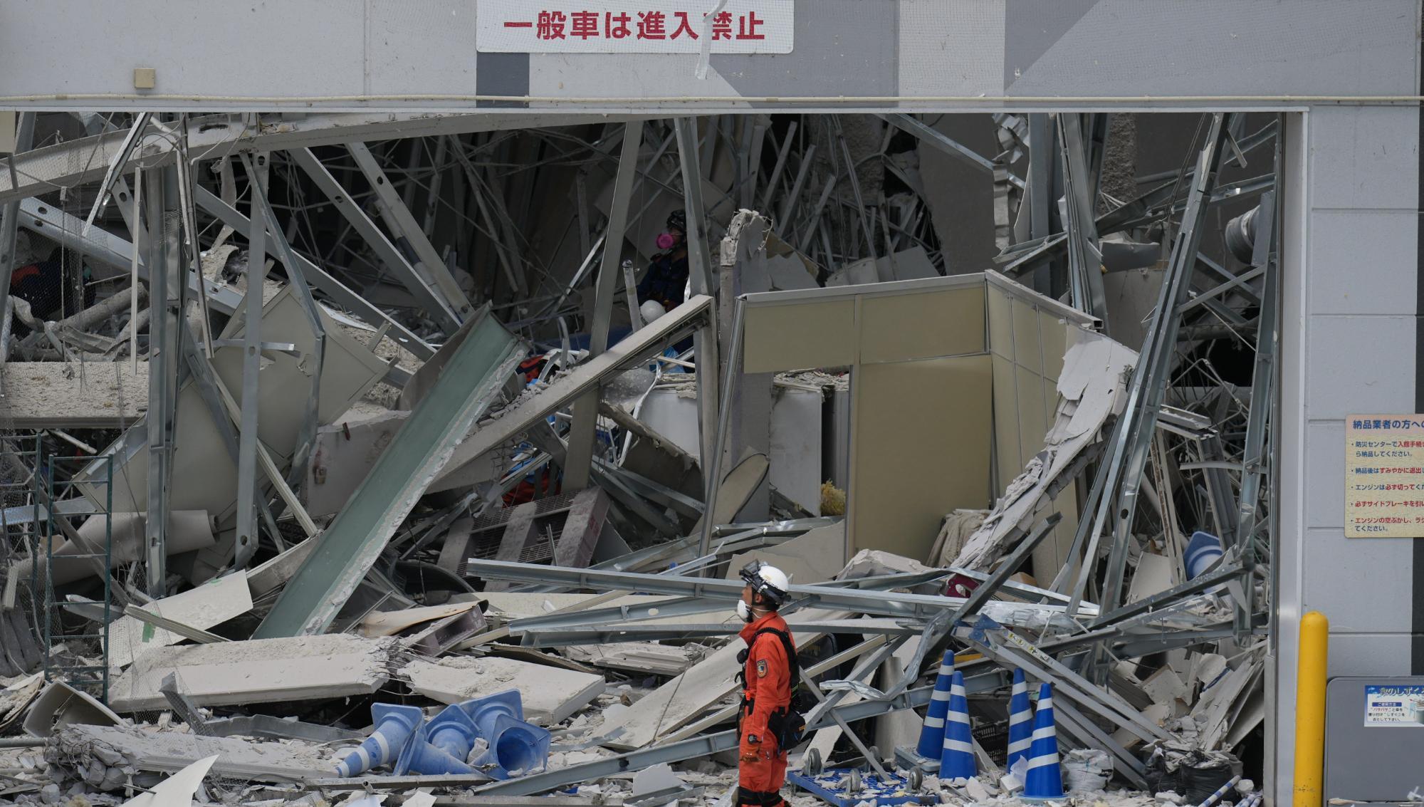Räddningsarbetare framför köpcentret AEON Mall i Kashima; byggnaden skadades av en explosion till följd av den kraftiga jordbävningen i Japan. Foto: Hiro Komae /AP/TT