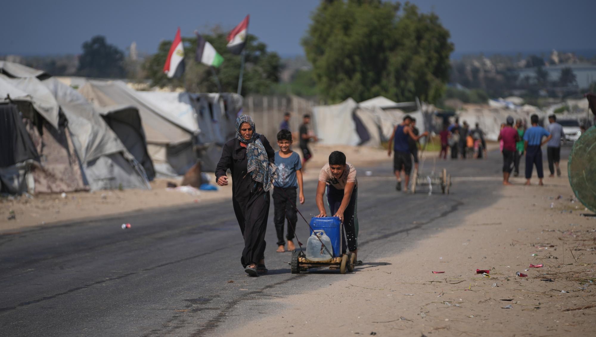 Civila transporterar vatten längs en väg i ett flyktingläger i Gaza under den pågående konflikten. Foto: Abdel Kareem Hana /AP/TT