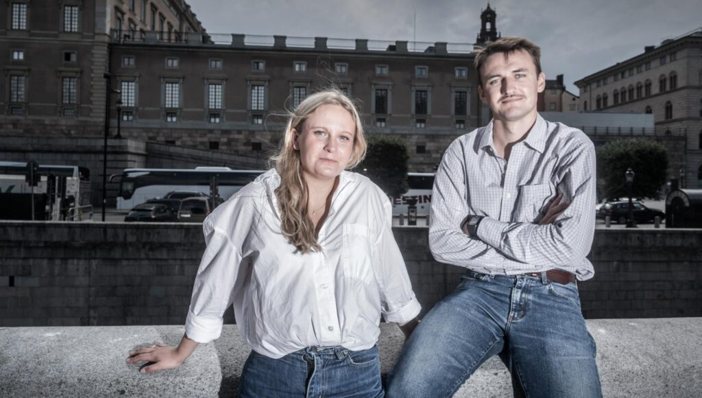 Kvinna och man i 20-årsåldern poserar framför Stockholms slott i dagsljus.