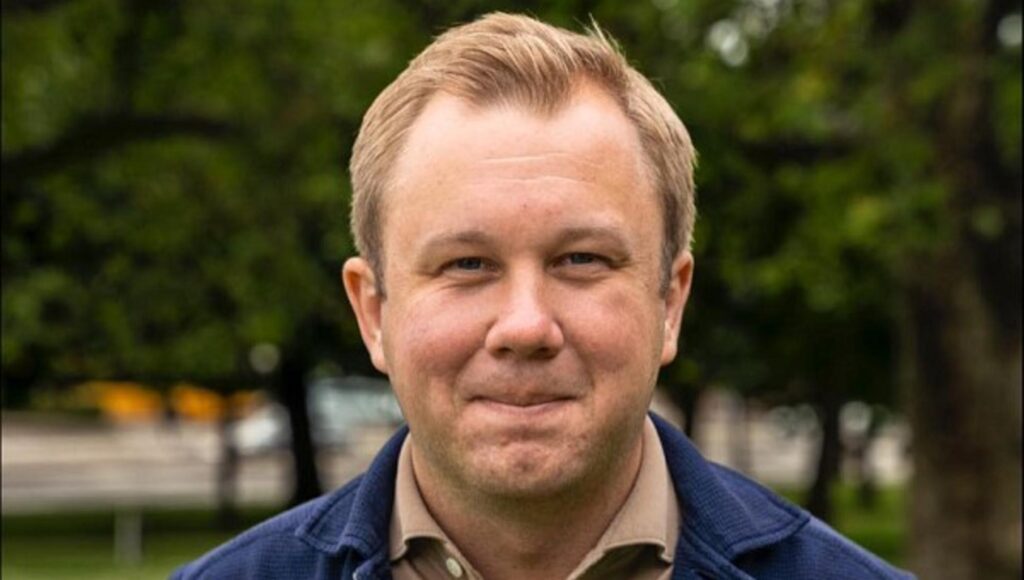 Porträtt på Johan Pehrson utomhus med grönskande träd i bakgrunden.